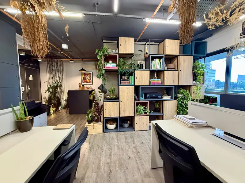 Área de trabalho do escritório da FR Prime em Alphaville, com estantes, plantas e janelas